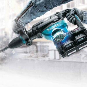 Des mains manipulent un perforateur sans fil makita très puissant qui perce dans du béton